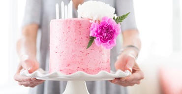 Person holding ceramic platter with pink cake on top