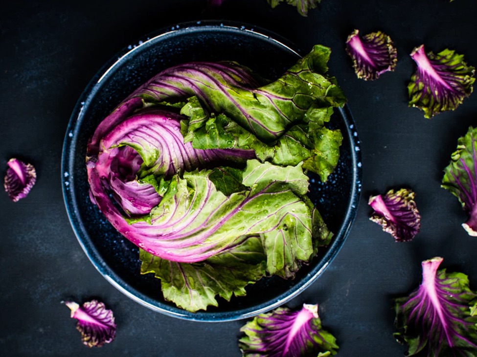 Purple kale in bowl and scattered on table