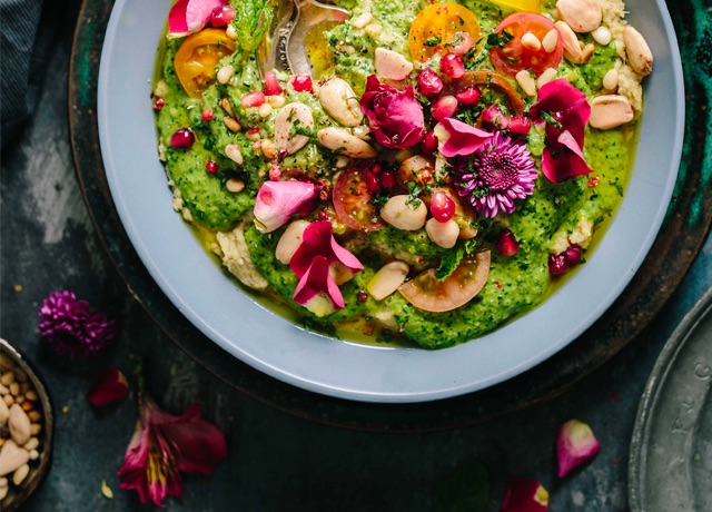 Bowl of guacamole with assorted nuts and veggies on top