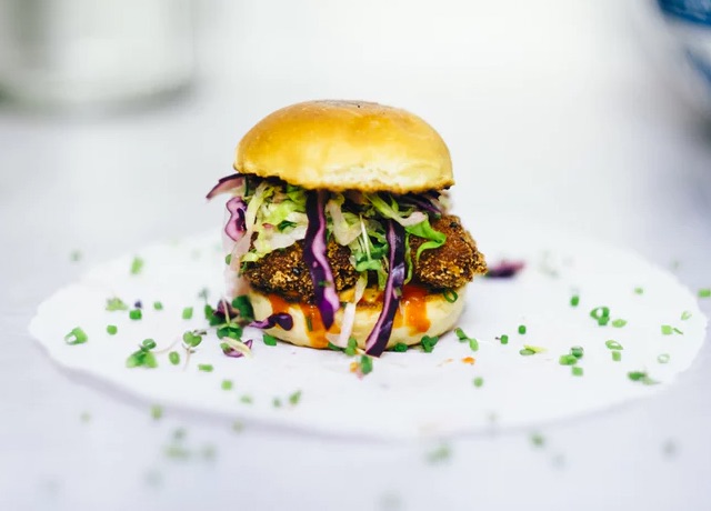 Large lettuce and cabbage-stuffed hamburger on plate, sprinkled with chives