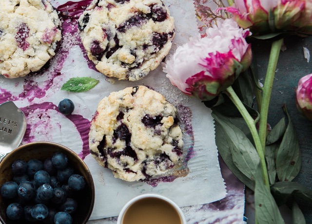 Blueberry cookies on parchment, surrounded by fresh blueberries and flowers